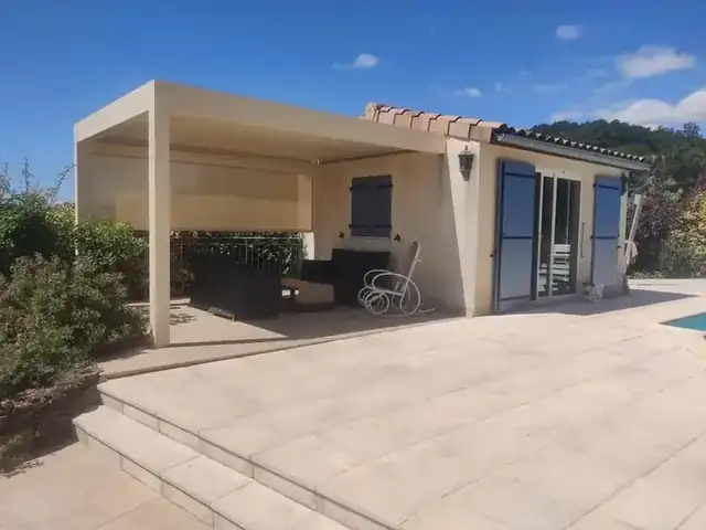 Une petite pergola avec store zippé au bord de la piscine