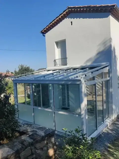 Une véranda à toiture vitrée et stores de toit