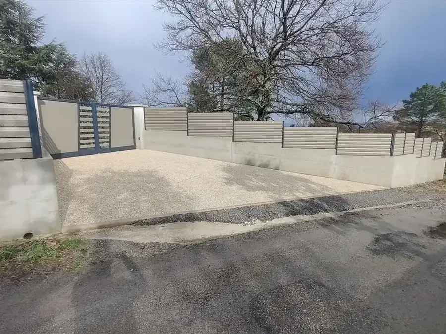 Allée, mur de soutènement et clôture beige menant au portail, chantier d'Aubenas