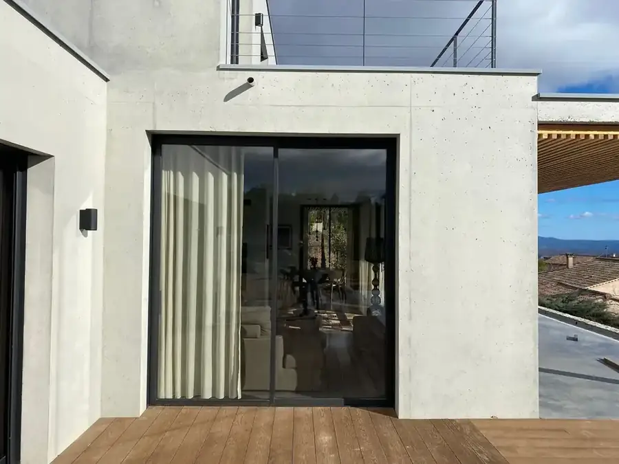 Baie coulissante aluminium noir ouverte sur une terrasse en bois