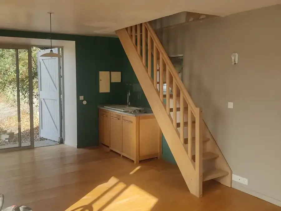 Pièce rénovée avec escalier droit en bois et kitchenette