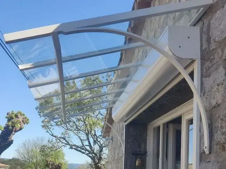 Marquise en acier laqué blanc et verre sur une façade en pierre