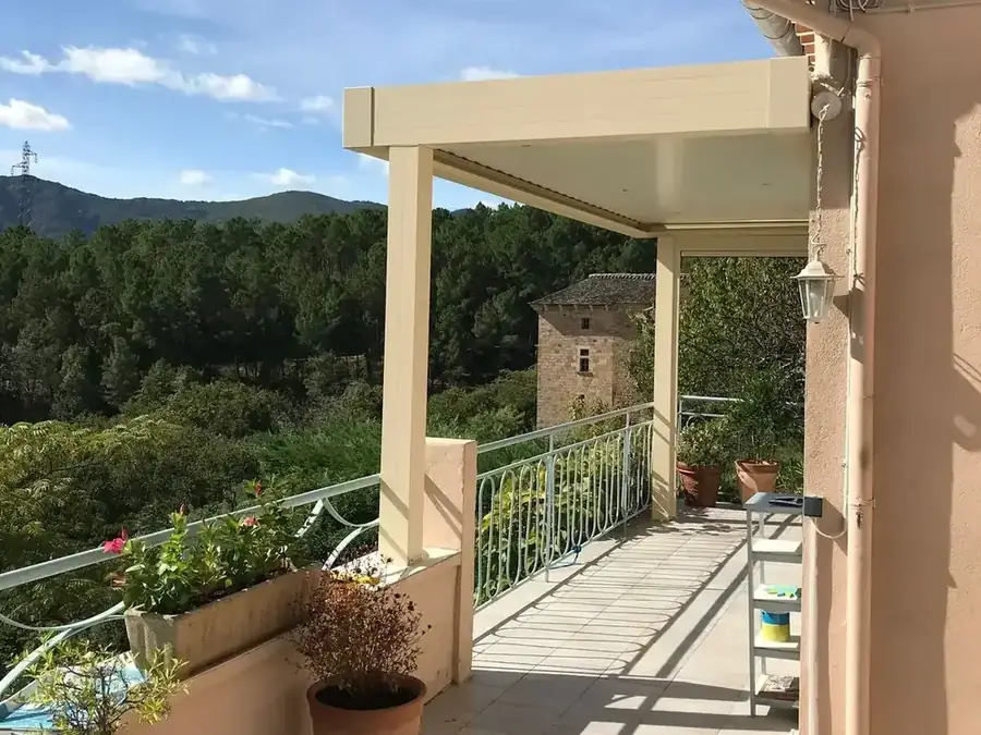 Pergola beige posée sur un balcon face aux collines boisées