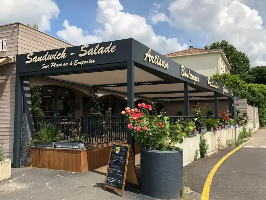 Pergola noire installée devant la terrasse d'une boulangerie