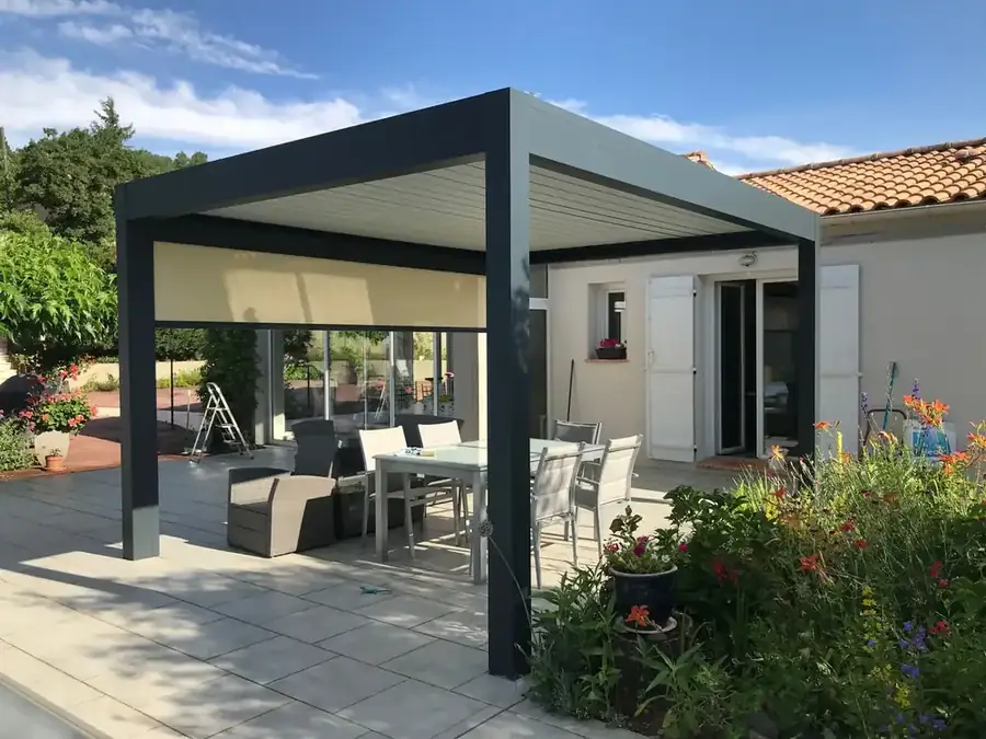 Pergola bioclimatique anthracite équipée d'un store vertical, terrasse et salon de jardin