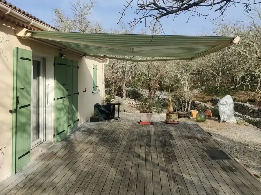 Store banne vert déployé au-dessus d’une terrasse en bois
