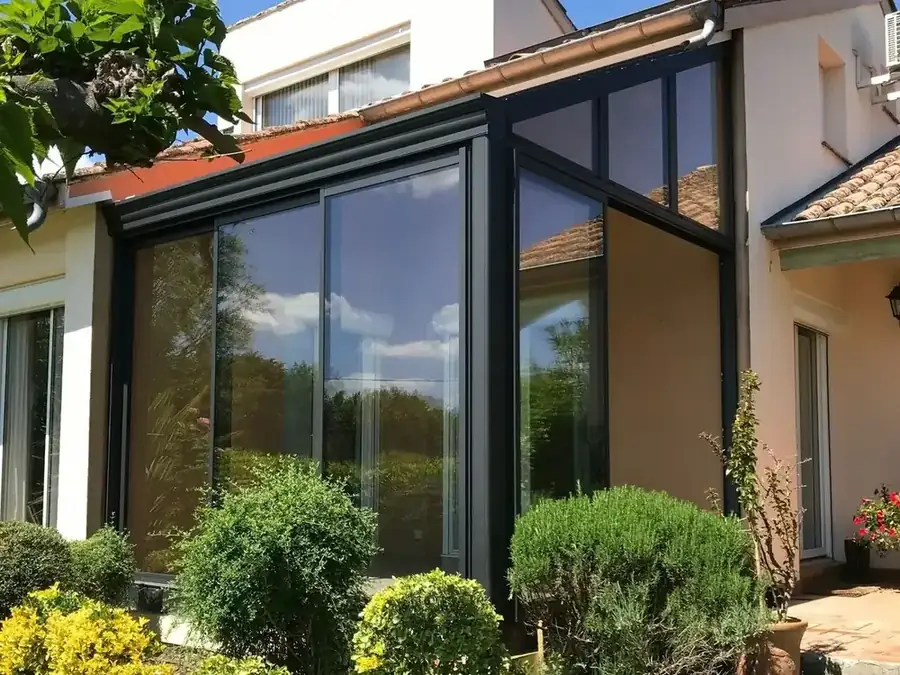 Véranda anthracite entièrement vitrée sur une maison crépie