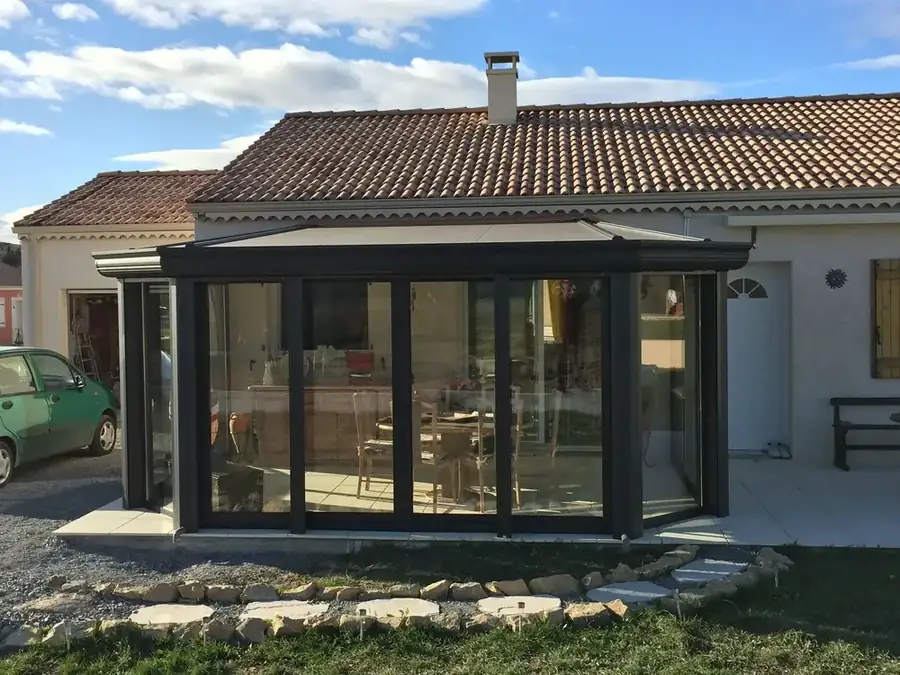 Véranda anthracite à pans sur une maison de plain-pied