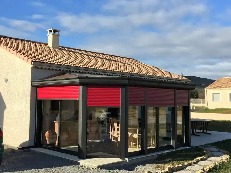Véranda anthracite équipée de volets roulants rouges