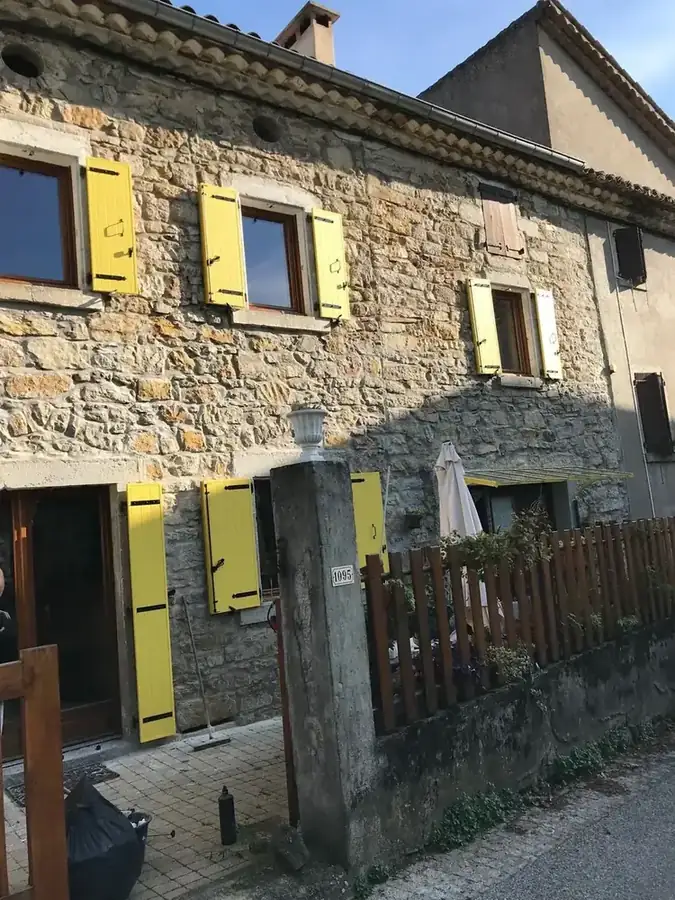 Maison en pierre aux volets battants jaunes